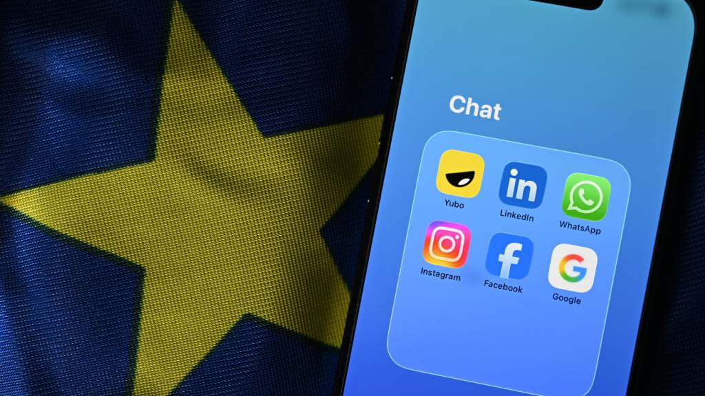 ILLUSTRATION - ILLUSTRATION - Die Apps Yubo, LinkedIn, WhatsApp, Facebook, Google und Instagram sind auf einem Smartphone in einer Gruppe mit dem Titel Chat zu sehe. Das Smartphone liegt auf einer EU-Flagge. (gestellte Szene). Foto: Markus Lenhardt/dpa