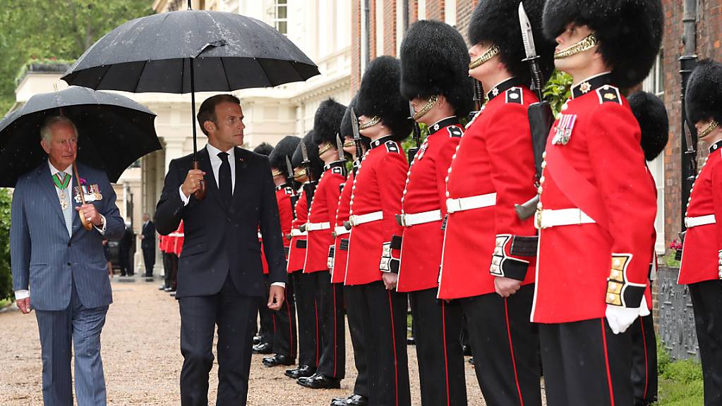 Der britische Prinz Charles (l), Prinz von Wales, und Emmanuel Macron (M), Präsident von Frankreich, gehen bei der Willkommenszeremonie die Grenadier-Garde im Clarence House ab. Foto: Jonathan Brady/PA Wire/dpa