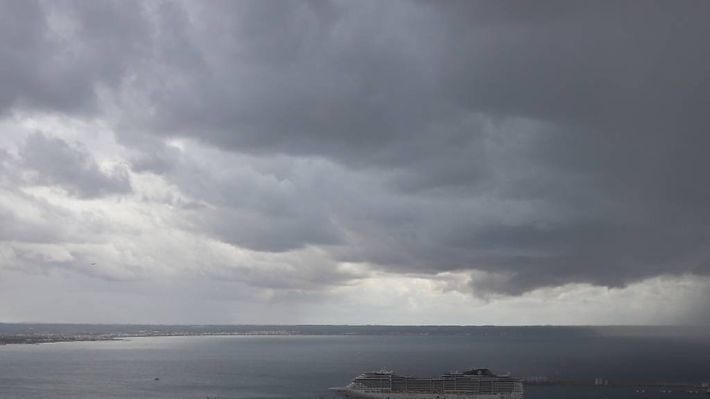 ARCHIV - Dunkle Regenwolken hängen über der Bucht und dem Hafen von Palma de Mallorca (Archivbild). Foto: Clara Margais/dpa