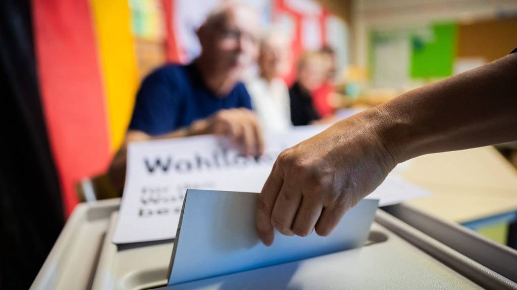 Eine Person wirft den Stimmzettel im Wahllokal in der Werbellinsee-Grundschule in Tempelhof-Schöneberg in eine Wahlurne. Foto: Christoph Soeder/dpa
