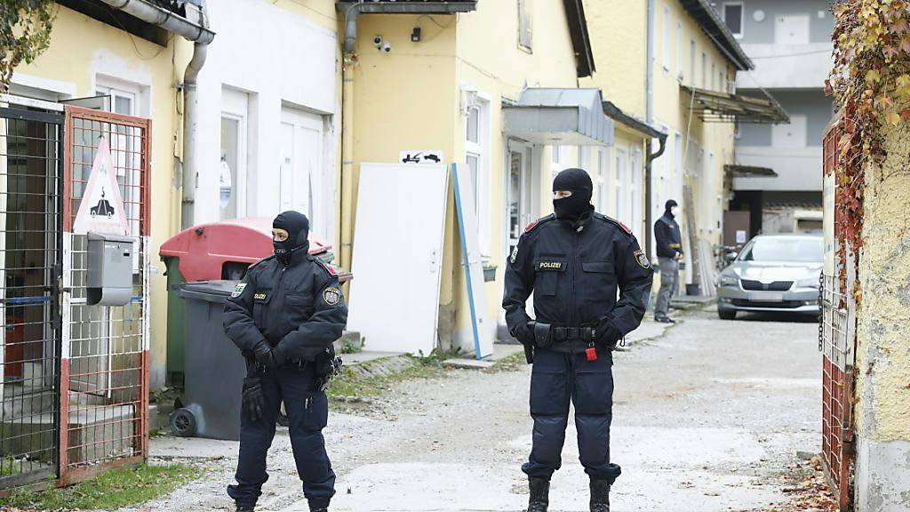 Zwei Polizisten stehen in einer Einfahrt an einem Einsatzort der Operation «Luxor» in Graz. Foto: Erwin Scheriau/APA/dpa - ACHTUNG: Die Kfz-Kennzeichen wurden aus persönlichkeitsrechtlichen Gründen gepixelt.