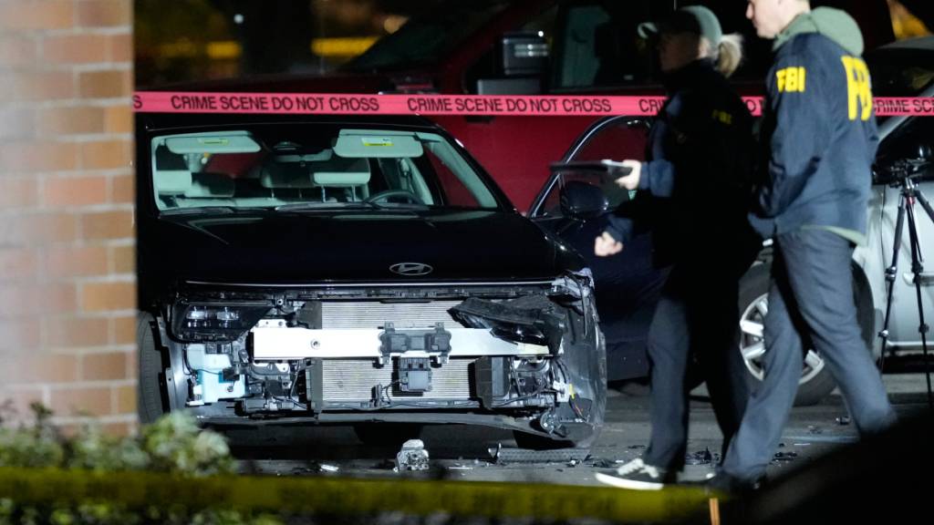 Ein beschädigtes Auto ist zu sehen, während Beamte den Tatort in Portland untersuchen. Foto: Jenny Kane/AP/dpa