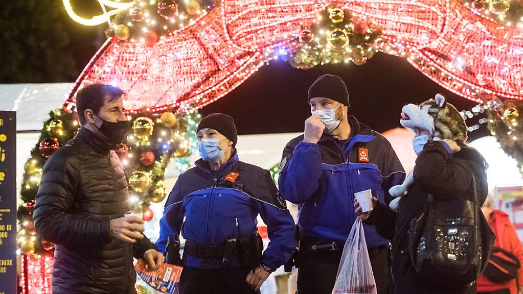Weihnachten während Zeiten Coronas: Polizisten und Besucher auf dem Weihnachtsmarkt auf der Piazza Riforma in Lugano. (Archivbild)