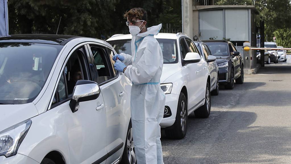 Ein medizinischer Mitarbeiter im Schutzanzug entnimmt an einer Drive-Thru-Station vor dem San Carlo Borromeo Krankenhaus Abstriche für Corona-Tests.