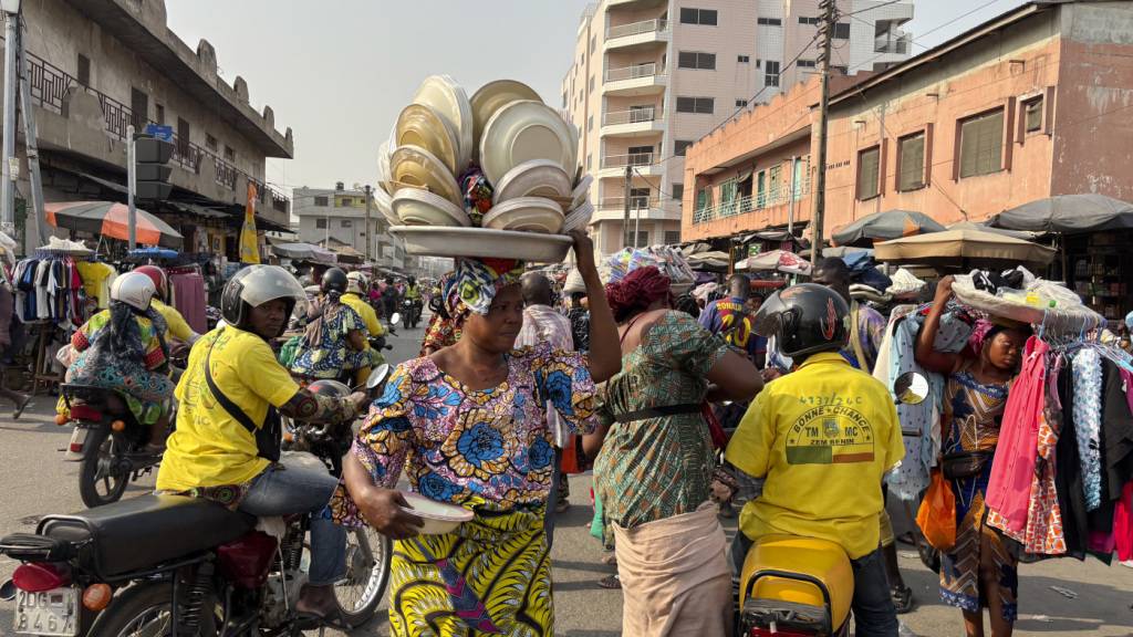 ARCHIV - Eine Tellerverkäuferin macht sich auf den Weg zum Markt in Cotonou. Foto: Sunday Alamba/AP/dpa