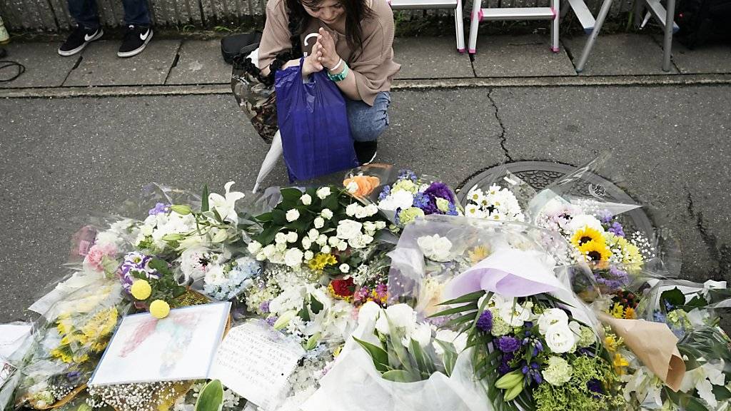 Nach dem Brandanschlag auf ein Trickfilm-Studio in Kyoto legen Anwohner Blumen nieder und beten für die Opfer.