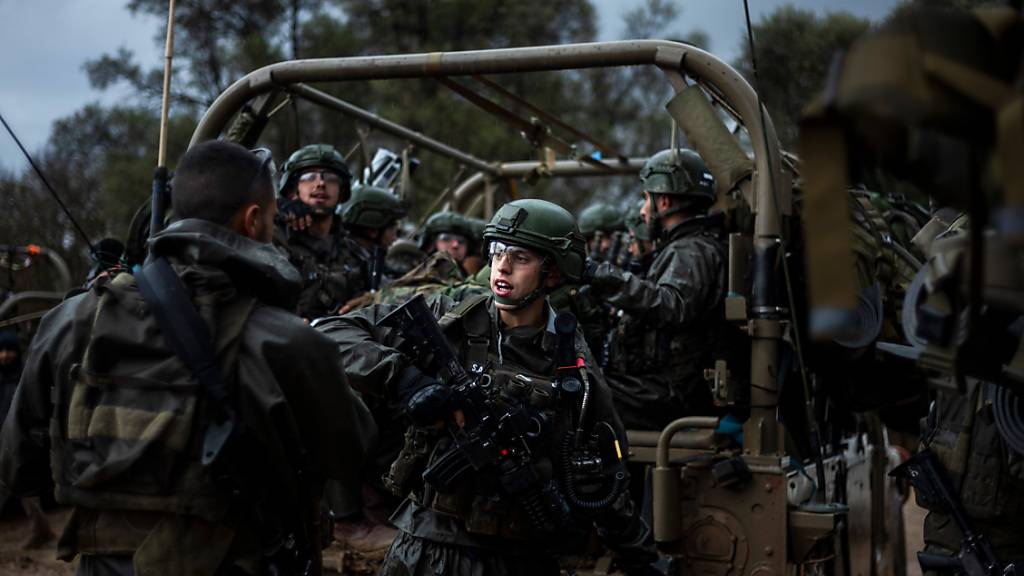 Israelische Soldaten sitzen in einem Militärfahrzeug an einem Sammlepunkt nahe der Grenze zum Gazastreifen. Foto: Ilia Yefimovich/dpa