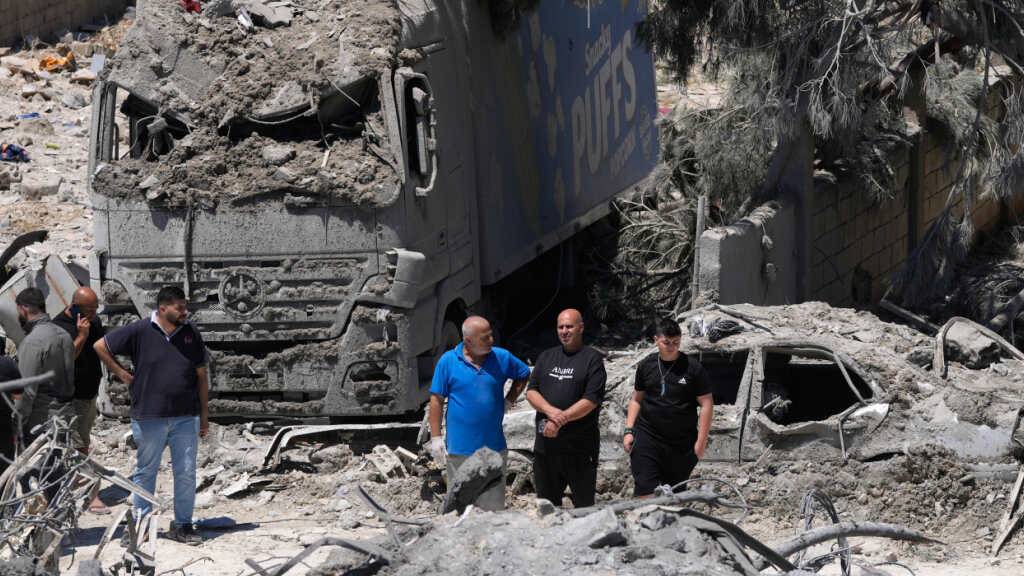 ARCHIV - Menschen versammeln sich an der Stelle eines zerstörten Gebäudes, das bei einem israelischen Luftangriff im Dorf Qannarit im Südlibanon getroffen wurde. Foto: Mohammed Zaatari/AP/dpa