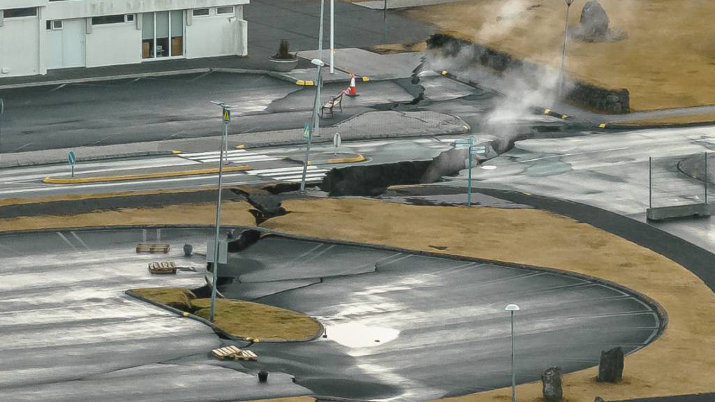 Aus Rissen im Boden neben einem Kinderspielplatz in der isl‰ndischen Stadt GrindavÌk steigt Rauch auf. Foto: Bjorn Steinbekk/AP/dpa