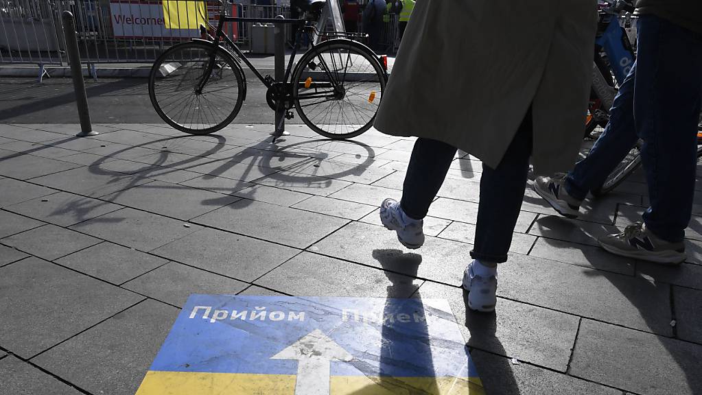 Ein Hinweisschild weist den ankommenden ukrainischen Flüchtlingen am Kölner Hauptbahnhof den Weg zur Erstversorgung.