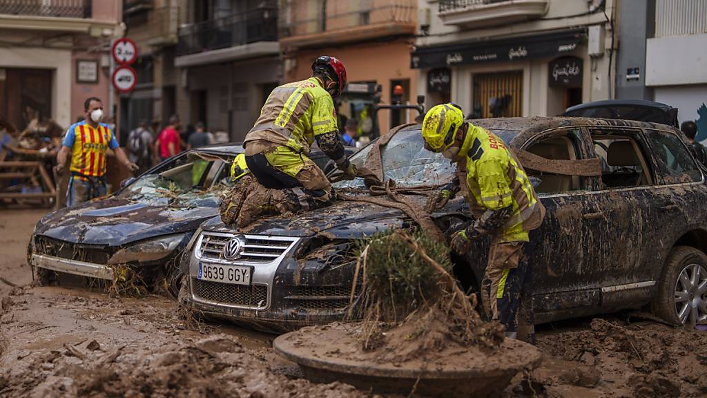 Feuerwehrleute entfernen ein Auto aus dem Schlamm in einem vom Hochwasser betroffenen Gebiet in Algemesi, Spanien. Foto: Manu Fernandez/AP/dpa