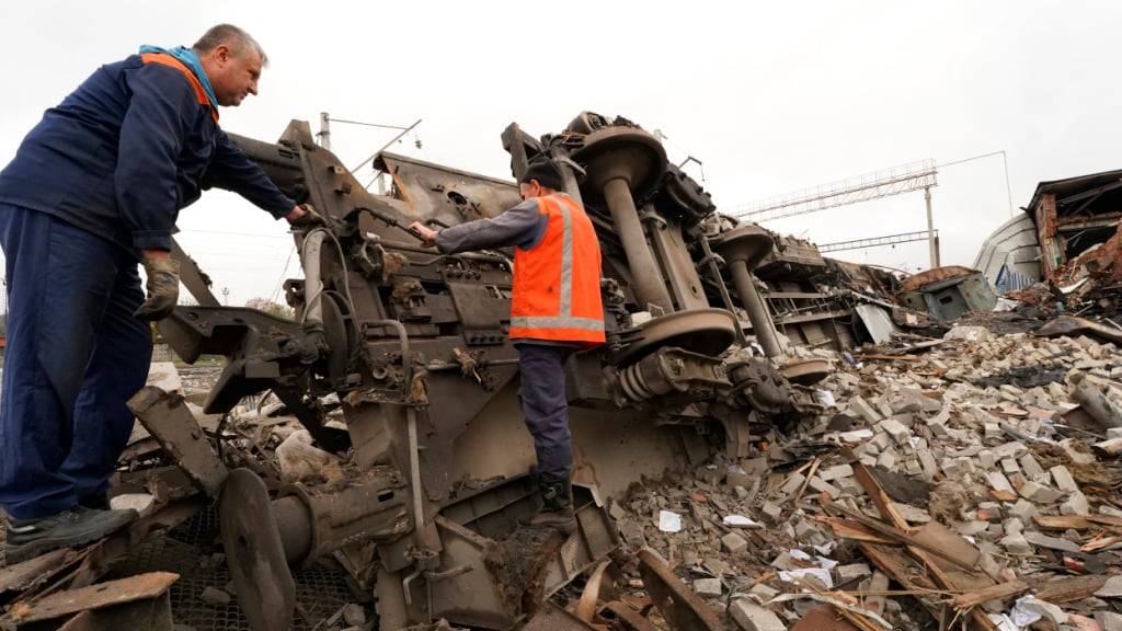 ARCHIV - Eisenbahner räumen die Trümmer auf, nachdem  ein Eisenbahndepot bei einem, mutmaßlich russischen, Raketenangriff zerstört wurde. Foto: Andrii Marienko/AP/dpa