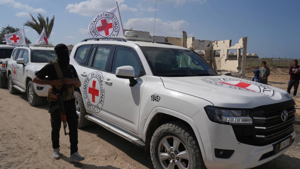 ARCHIV - Ein maskierter Hamas-Bewaffneter steht neben Fahrzeugen des Roten Kreuzes. Foto: Abdel Kareem Hana/AP/dpa/Symbolbild