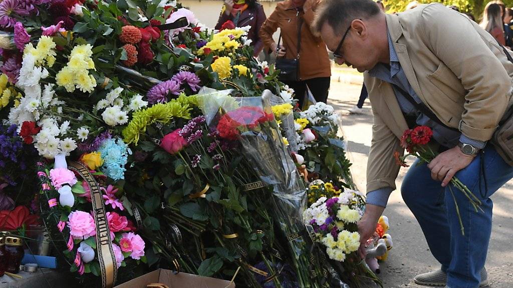 Ein Mann legt an der Schule Blumen für die Opfer nieder.