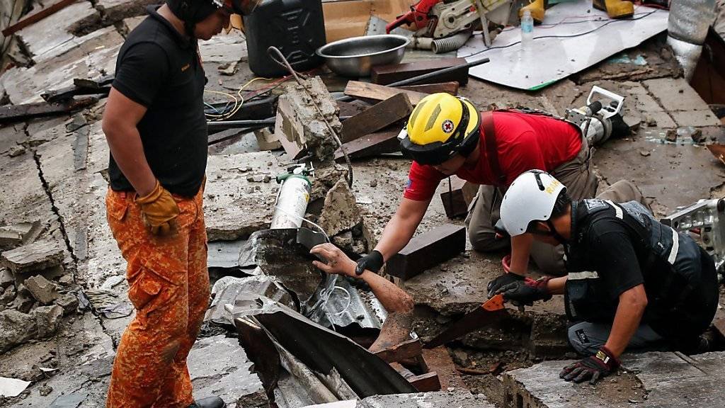 Rettunskräfte bergen einen Mann, der bei einem Mauereinsturz während eines Unwetters in Manila verschüttet wurde.