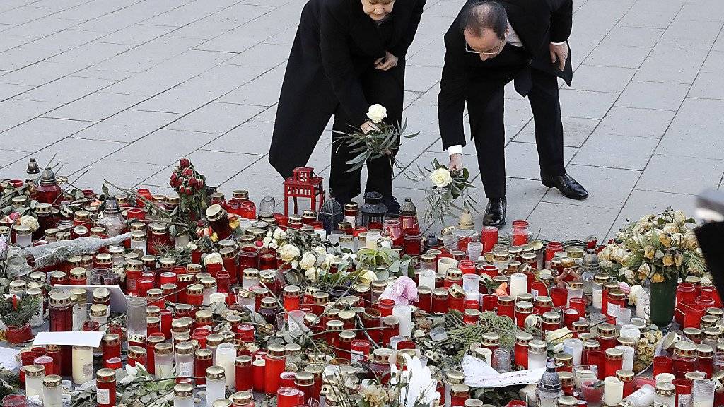 Die deutsche Kanzlerin Merkel und der französische Präsident Hollande legen zum Gedenken an die Opfer des Anschlags auf einen Berliner Weihnachtsmarkt Blumen nieder.