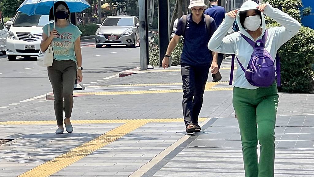 ARCHIV - Menschen auf der Silom Road in Bangkok versuchen, sich vor der Hitze zu schützen. Foto: Carola Frentzen/dpa