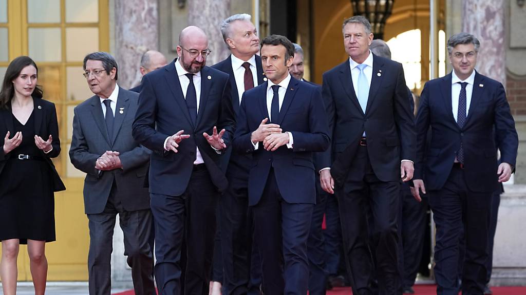 Emmanuel Macron (M), Präsident von Frankreich, spricht mit Charles Michel (Mitte l), Präsident des Europäischen Rates, auf dem Weg zu einem Gruppenfoto während eines informellen Gipfels der EU-Staats- und Regierungschefs im Schloss von Versailles. Foto: Michel Euler/AP/dpa
