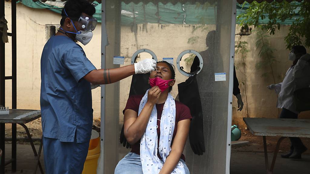 Ein Mitarbeiter des Gesundheitswesens entnimmt einer Frau einen Nasenabstrich. Foto: Mahesh Kumar A/AP/dpa