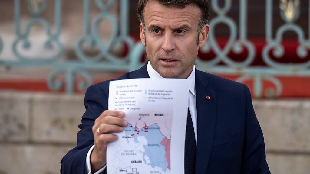 Der französische Präsident Emmanuel Macron zeigt eine Grafik zum Angriff auf die Ukraine. Foto: Michael Kappeler/dpa