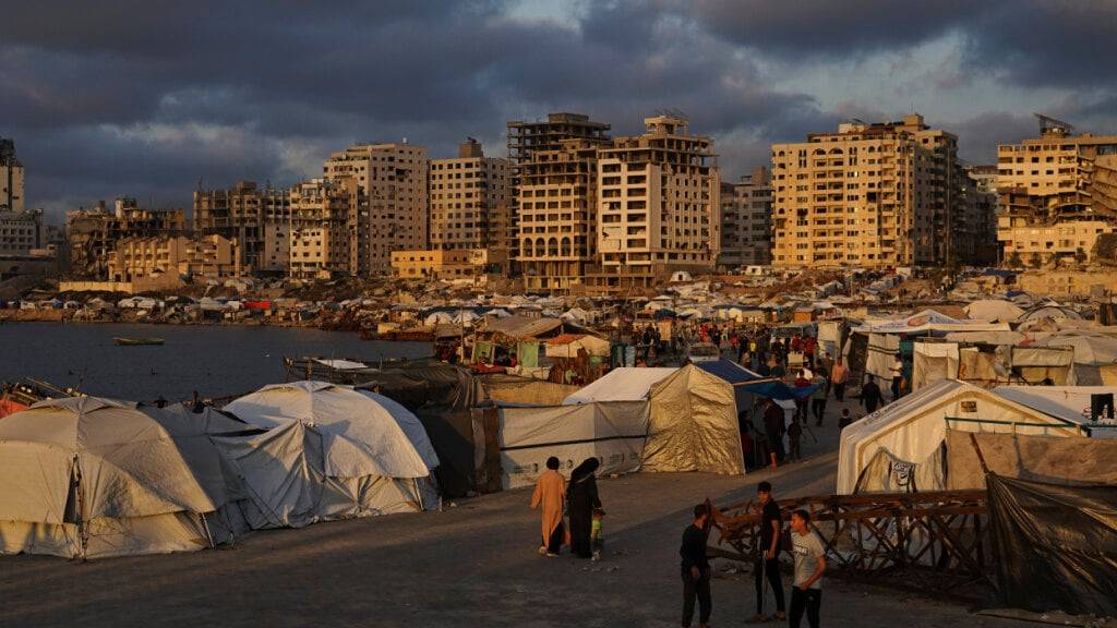 dpatopbilder - Vertriebene Palästinenser gehen an einem behelfsmäßigen Zeltlager an der Küste entlang. Foto: Jehad Alshrafi/AP/dpa