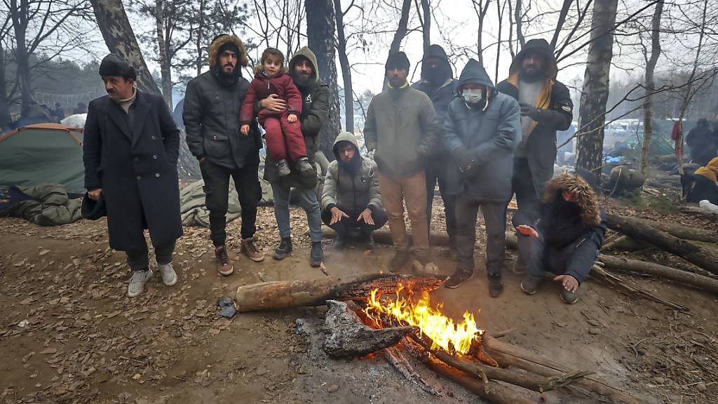 Migranten stehen an der belarussisch-polnischen Grenze an einem Feuer. Foto: Ramil Nasibulin/BelTA/AP/dpa
