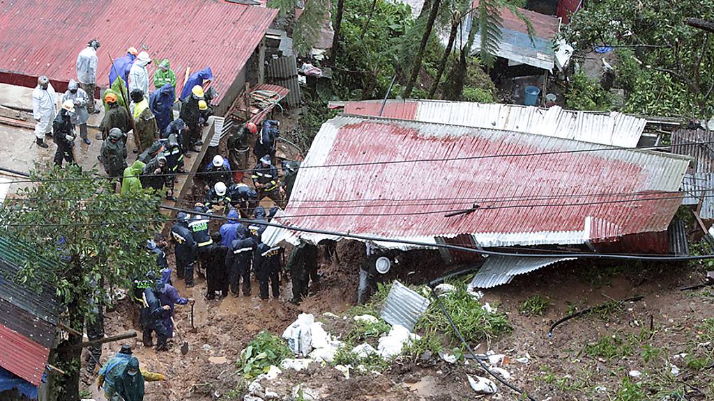 Rettungskräfte auf den Philippinen suchen in einem Haus nach Opfern. Das Haus wurde durch den Tropensturm Kompasu verursachten Erdrutsch verschüttet. Foto: Uncredited/AP/dpa
