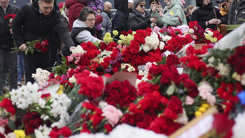 dpatopbilder - Menschen legen Blumen vor der Crocus City Hall nieder. In der Konzerthalle in einem Moskauer Vorort hatten Bewaffnete das Feuer auf Konzertbesucher eröffnet. Die Zahl der Todesopfer stieg laut russischen Behörden über 135. Foto: Vitaly Smolnikov/AP/dpa