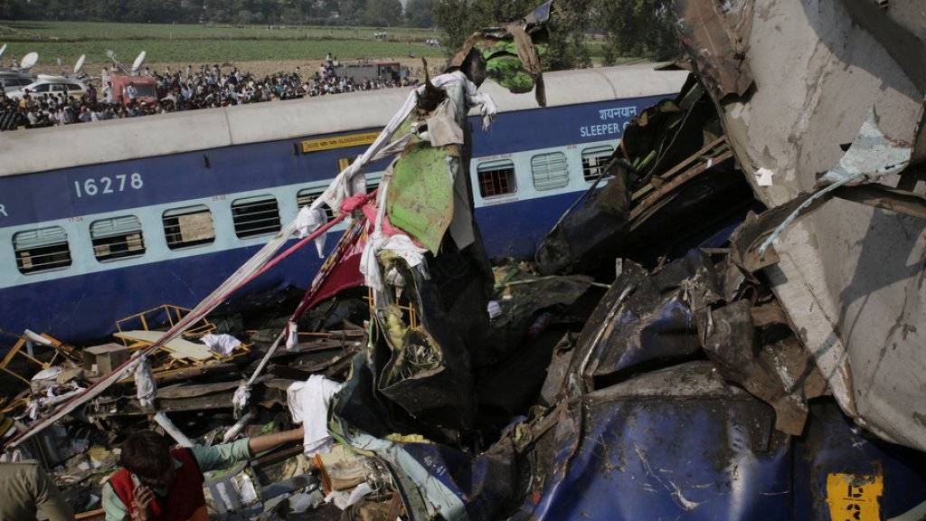 Rettungskräfte suchen in den völlig zerstörten Eisenbahnwagen nach Überlebenden. Beim Zugunglück in Indien kamen fast 100 Menschen ums Leben.