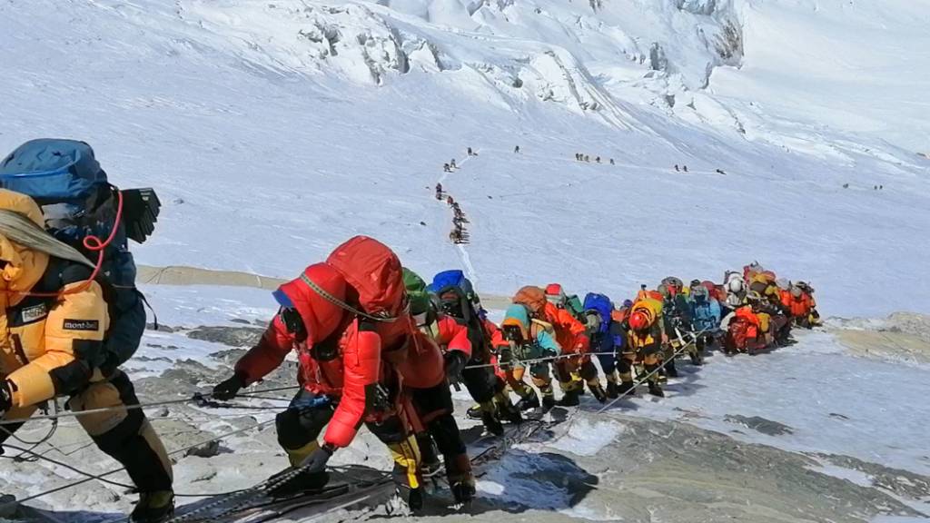 ARCHIV - In einer langer Schlange klettern Bergsteiger auf einem Pfad knapp unterhalb von Lager vier. Erfahrene Sherpa-Bergführer in Nepal haben begonnen, die Routen auf den Mount Everest und andere Himalaya-Berge für Bergsteiger aus dem Ausland vorzubereiten. Foto: Rizza Alee/AP/dpa