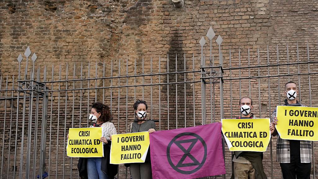 Klimaaktivisten von Extinction Rebellion ketten sich mit Fahrradschlössern an einen Zaun und halten Schilder während einer Demonstration vor dem G20-Gipfel hoch.