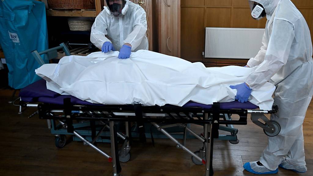 Bestatter in London kümmern sich in Schutzkleidern um ein Corona-Todesopfer.