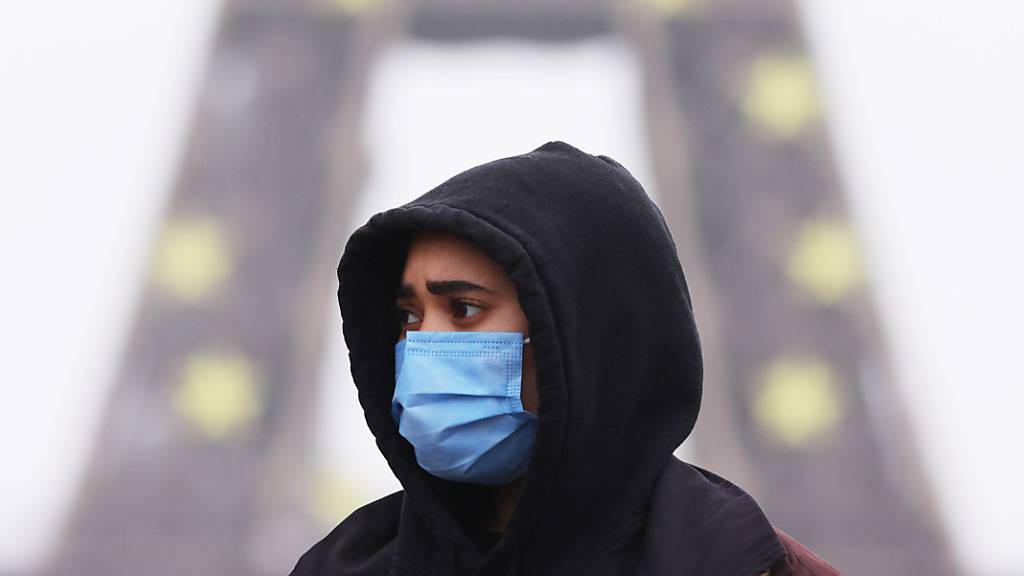 Eine Frau trägt eine Schutzmaske und geht am Trocadero in der Nähe des Eiffelturms spazieren. Als Reaktion auf steigende Corona-Infektionszahlen wird die Maskenpflicht in Paris ausgeweitet. Foto: Gao Jing/XinHua/dpa