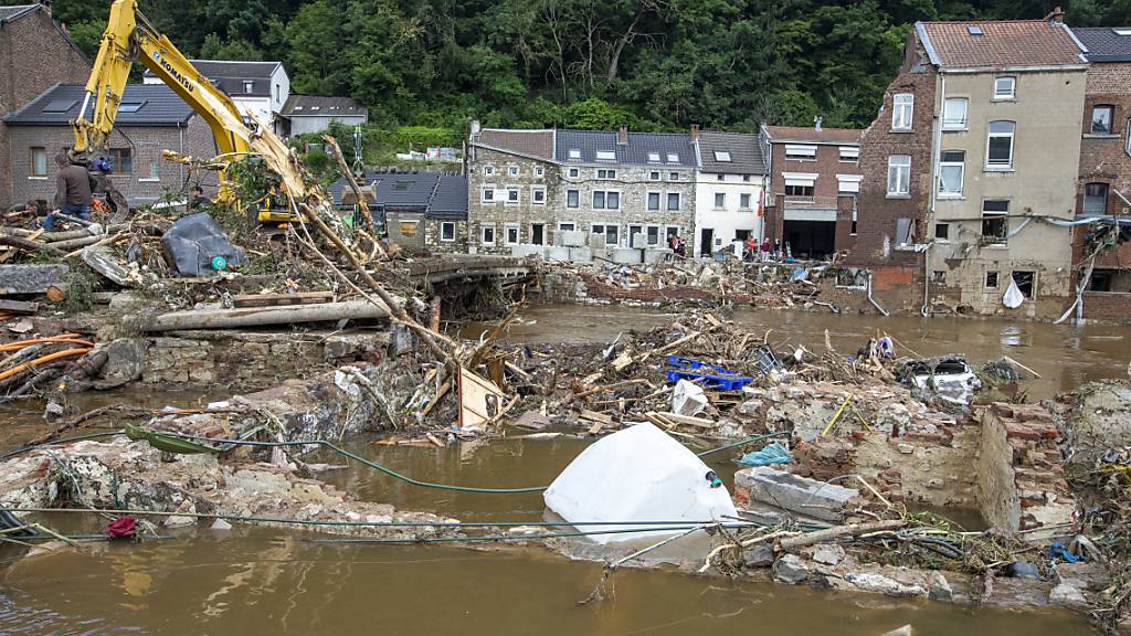 Anwohner im Ort Pepinster beseitigen Trümmer mit einem Bagger. Foto: Nicolas Maeterlinck/BELGA/dpa