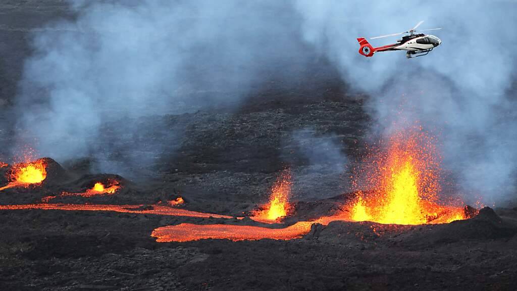 dpatopbilder - Ein Hubschrauber fliegt über dem ausbrechenden Vulkan Piton de la Fournaise auf der französischen Insel Reunion im Indischen Ozean. (Archivbild) Foto: Richard Bouhet/AFP/dpa