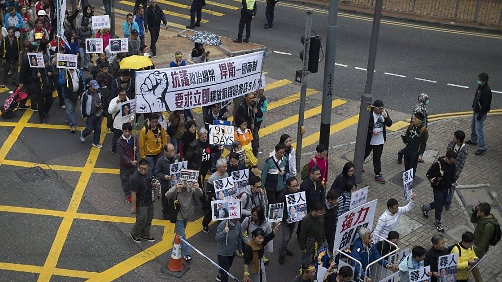 Tausende fordern in Hongkong Aufklärung über den Verbleib von fünf Mitarbeitern eines chinakritischen Verlags. «Nein zu politisch motivierten Entführungen!», heisst es auf den Plakaten.