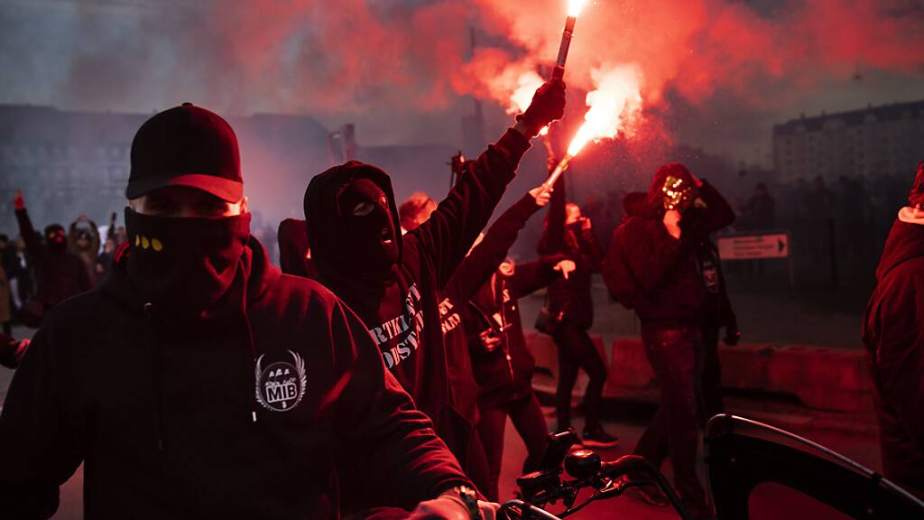 Anhänger der Gruppe «Men in Black» protestieren mit Bengalos gegen die Corona-Maßnahmen der Regierung auf der Straße in Kopenhagen. Foto: Martin Sylvest/Ritzau Scanpix/AP/dpa