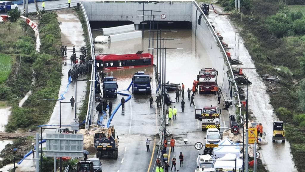 Rettungskräfte suchen nach Überlebenden auf einer Straße, die von Fluten überschwemmt wurde und zu einem unterirdischen Tunnel führt. Foto: Kim Ju-hyung/Yonhap/AP/dpa