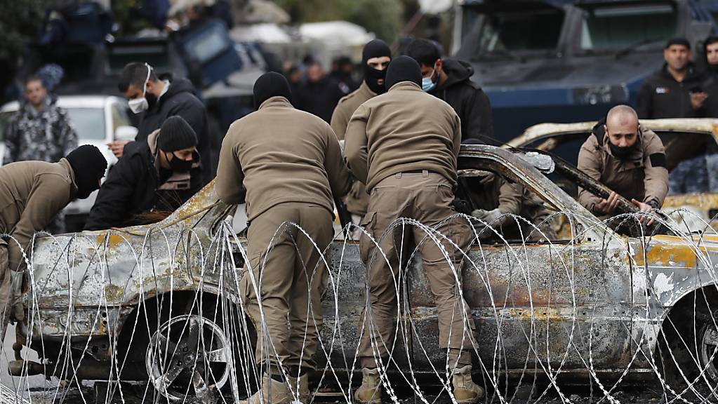 Polizeibeamte entfernen in Tripoli ein Auto, das von Demonstranten während gewaltsamen Auseinandersetzungen mit Sicherheitskräften in Brand gesetzt wurde.
