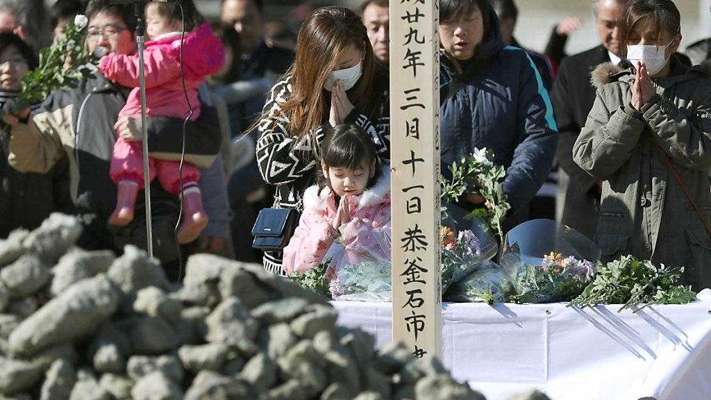 Angehörige gedenken der Opfer des Erdbebens und des Tsunamis vom  11. März 2011.