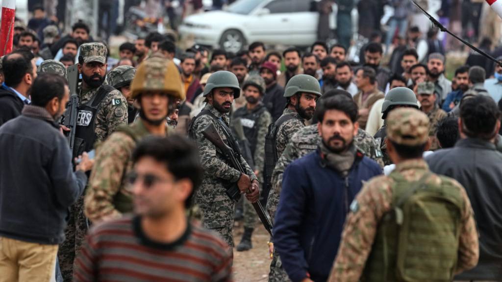 Sicherheitskräfte sind nach einem Anschlag auf ein schiitisches Gemeindehaus vor Ort und kontrollieren eine Menschenmenge. Foto: Anjum Naveed/AP/dpa