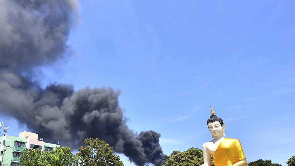 Rauch steigt hinter einer riesigen Buddha-Statue in der Provinz Samut Prakan auf. In Thailand ist es in einer Chemiefabrik zu einer schweren Explosion gekommen. Foto: Uncredited/AP/dpa