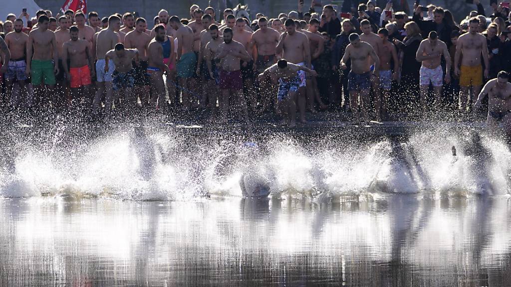 Christlich-Orthodoxe Gläubige springen während des traditionellen Dreikönigsfestes in das kalte Wasser des Becmen-Sees in Serbien.