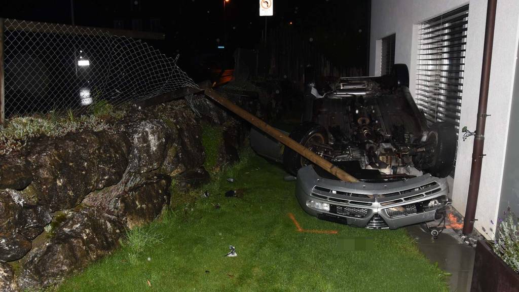 Mann «parkiert» Auto auf dem Dach liegend in Garten