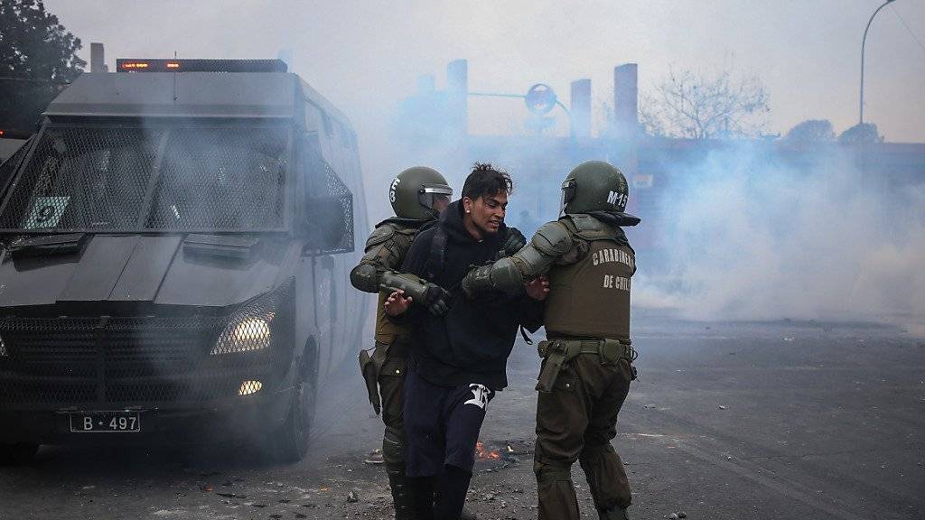 Nach schweren Ausschreitungen bei einer Demonstration zum Jahrestag des Staatsstreichs in Chile nehmen Polizisten einen Mann fest.
