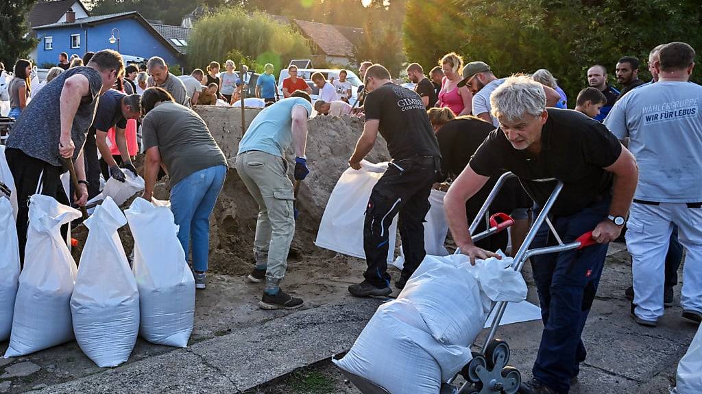 dpatopbilder - Einwohner befüllen Sandsäcke gegen das drohende Hochwasser. Foto: Patrick Pleul/dpa