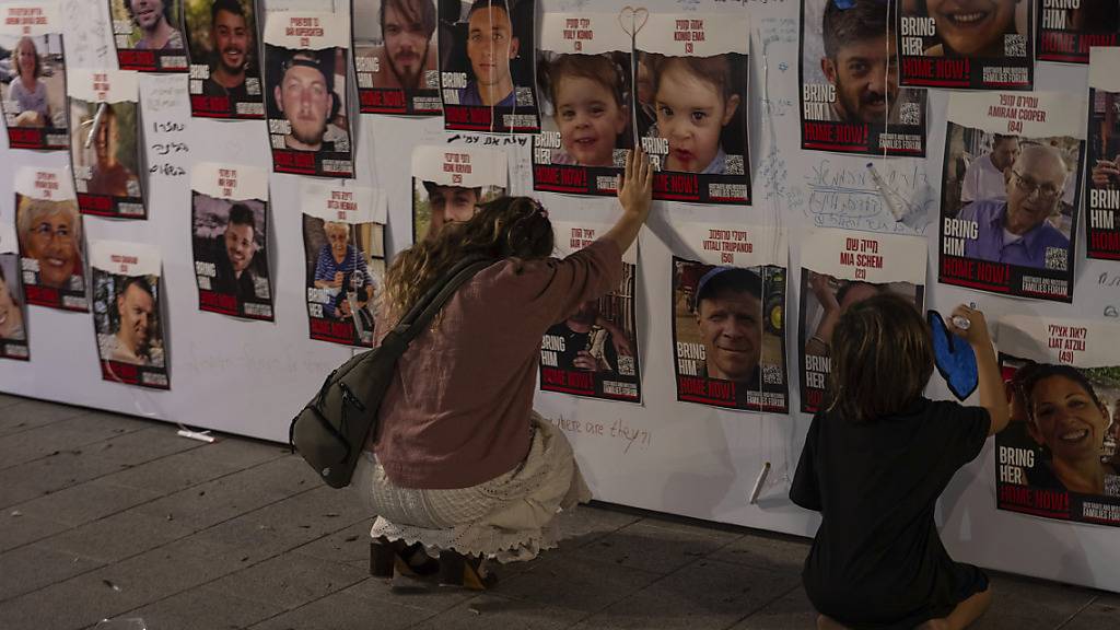 dpatopbilder - Eine israelische Frau berührt Fotos von in Gaza vermissten und gefangen gehaltenen Israelis. Foto: Petros Giannakouris/AP/dpa