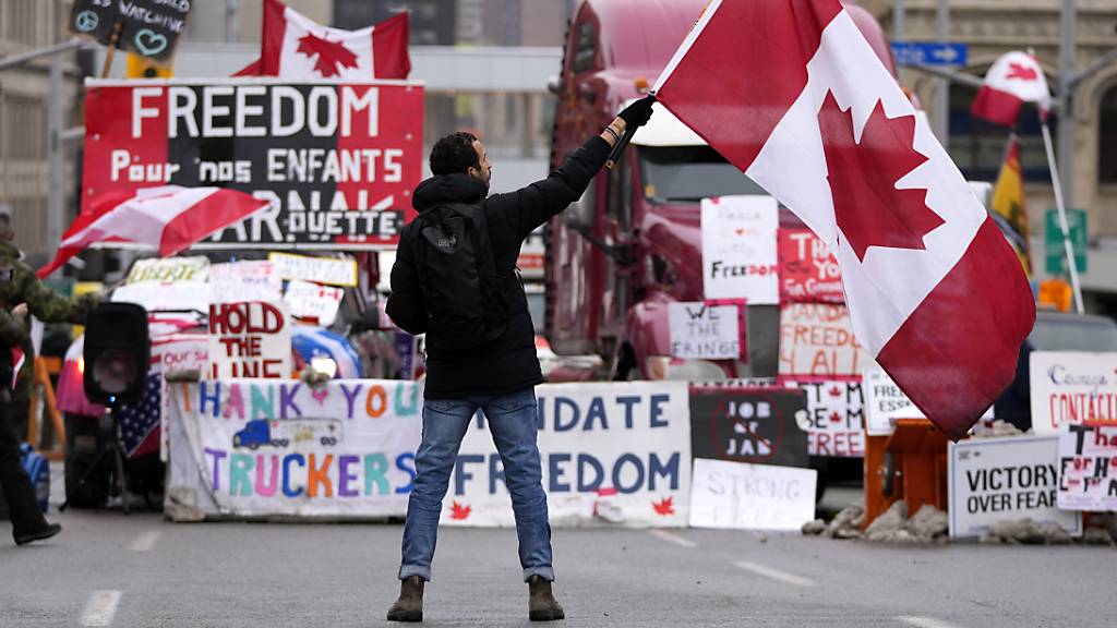 Ein Demonstrant schwenkt bei einem Protest gegen die Corona-Maßnahmen in Ottawa eine kanadische Flagge. Am Wochenende haben kanadische Trucker trotz mehrerer Polizeieinsätze ihre Proteste gegen die Corona-Maßnahmen der Regierung fortgesetzt. Foto: Justin Tang/The Canadian Press/dpa