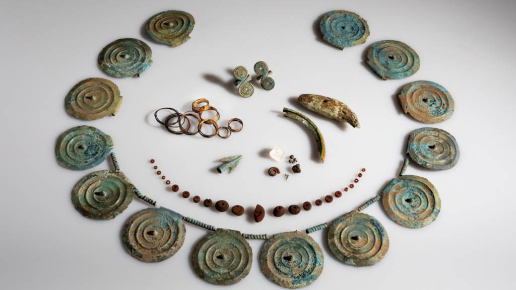 Der Fund der Archäologen umfasst ein Collier mit Stachelscheiben, eine Bernsteinkette, Fingerringe, Goldspiralen und einen Bärenzahn oder Ammoniten.