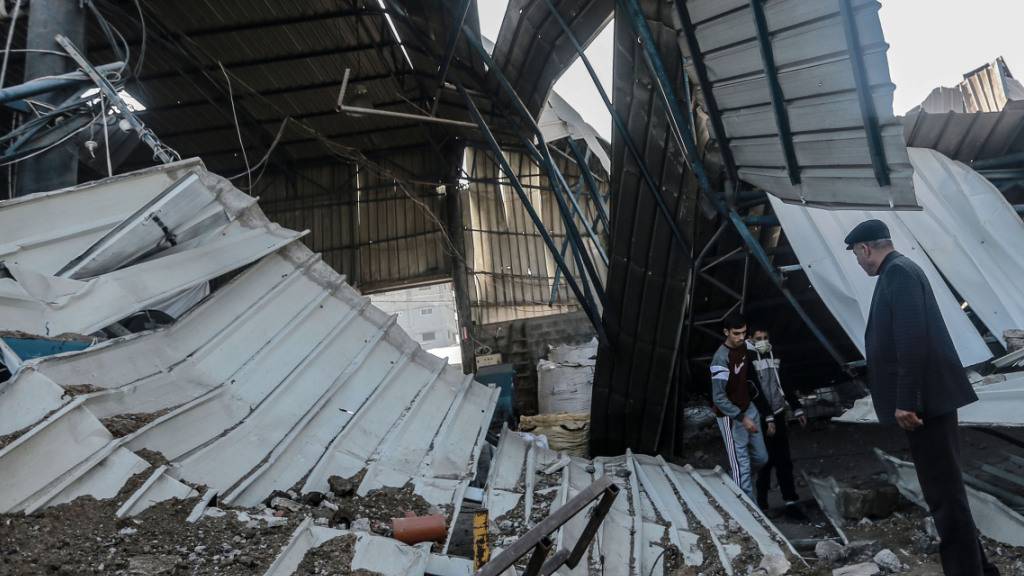 Männer untersuchen die Schäden in einer Werkstatt. Israelische Kampfflugzeuge haben in der Nacht zum Samstag Stellungen der islamistischen Hamas im Gazastreifen angegriffen. Foto: Mohammed Talatene/dpa